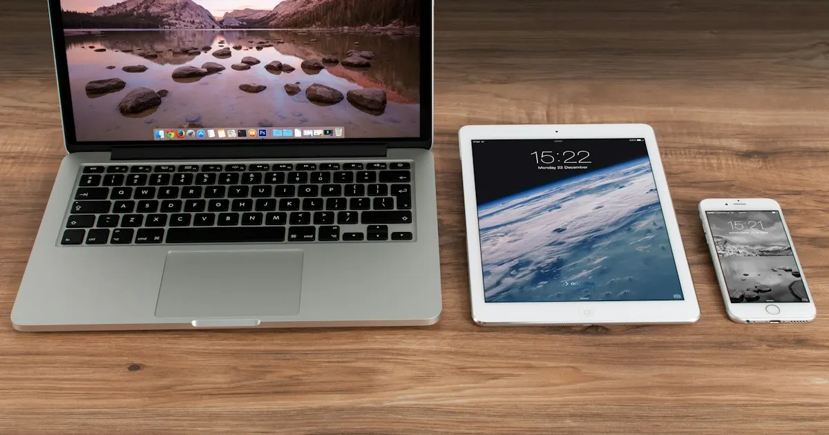 Laptop, tablet, and phone lined up on a wooden desk